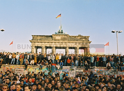 Bewohner aus West- und Ostberlin stehen auf der Mauerkrone am Brandenburger Tor, Nov. 1989